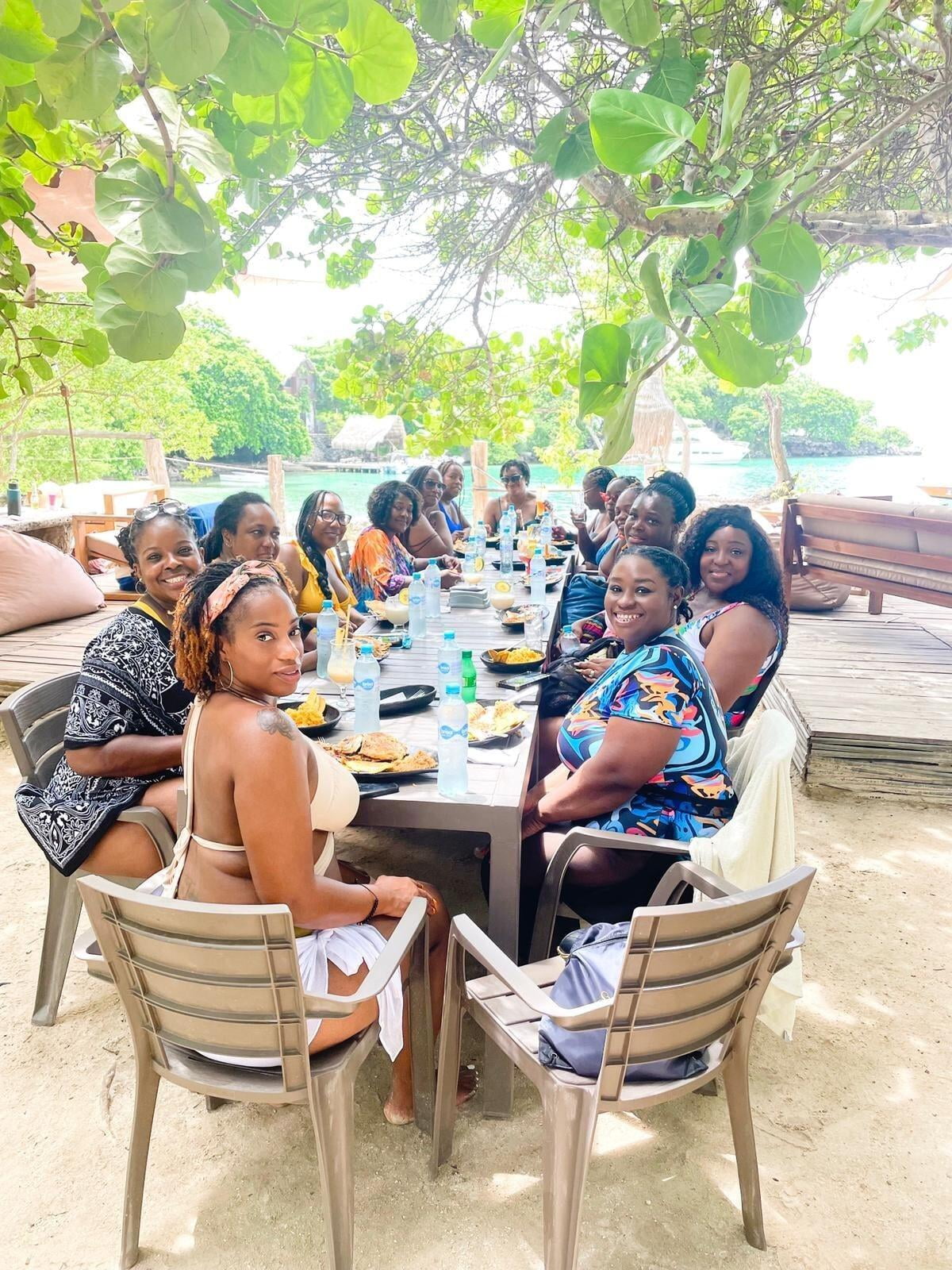 group of women sitting at a lunch table with the view of the ocean in the background