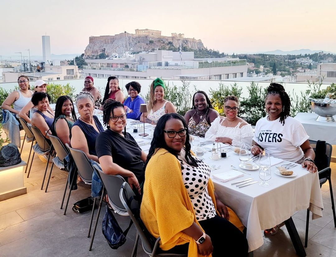 group of women sitting at a lunch table with the view of the ocean in the background